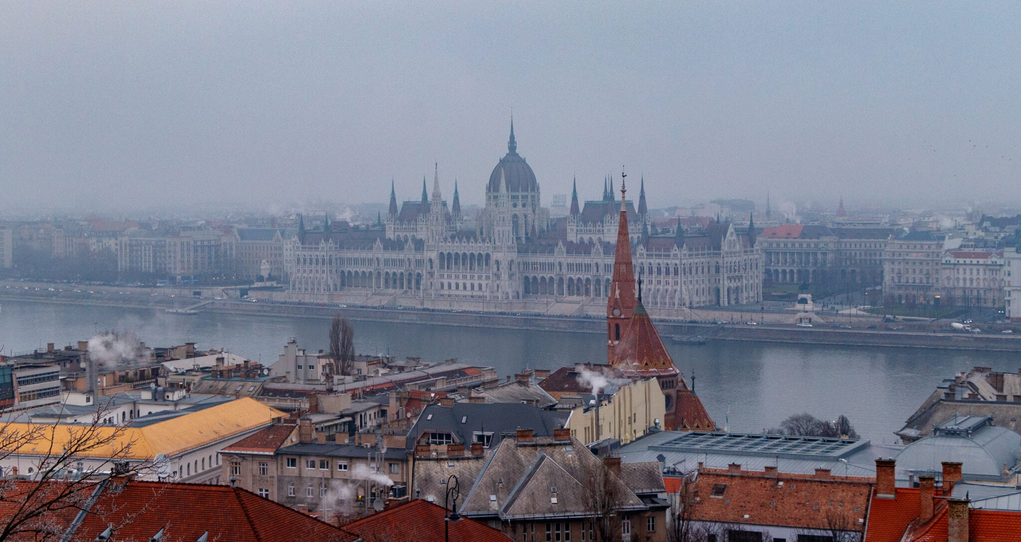 Winter panorama of Budapest in the fog. The neo-Gothic building of the Hungarian Parliament on the banks of the Danube in January.