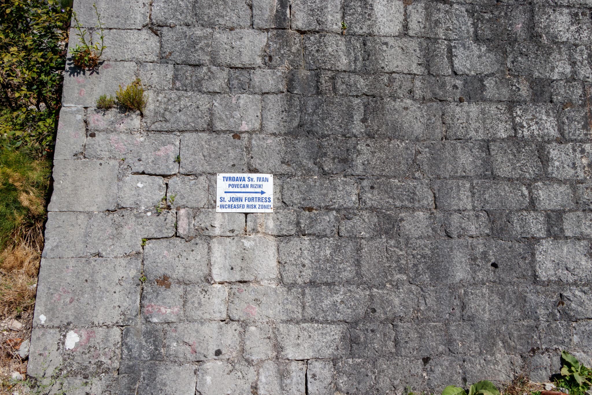 A plaque with the direction of the entrance to the Kotor Fortress - a high-risk zone. Montenegro.